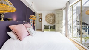 Un dormitorio moderno con una cama grande, una lámpara colgante de ratán y vistas al balcón exterior.