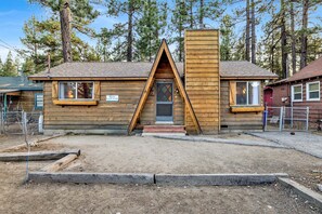 A wooden cabin with a triangular roof, a chimney, and a small porch. - Bernhardt Brown Bungalow #2583 (Big Bear City)