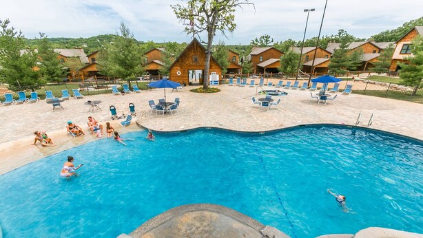 Un espace piscine avec des chaises longues et un chalet en bois en arrière-plan.