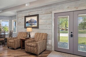 Ein gemütliches Wohnzimmer mit zwei gemusterten Sesseln, einem Holztisch und einem gerahmten Bild an der Wand.