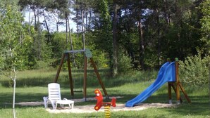 A playground with a swing set, a slide, and a red seesaw. - hôtel le grand chêne (Gièvres)