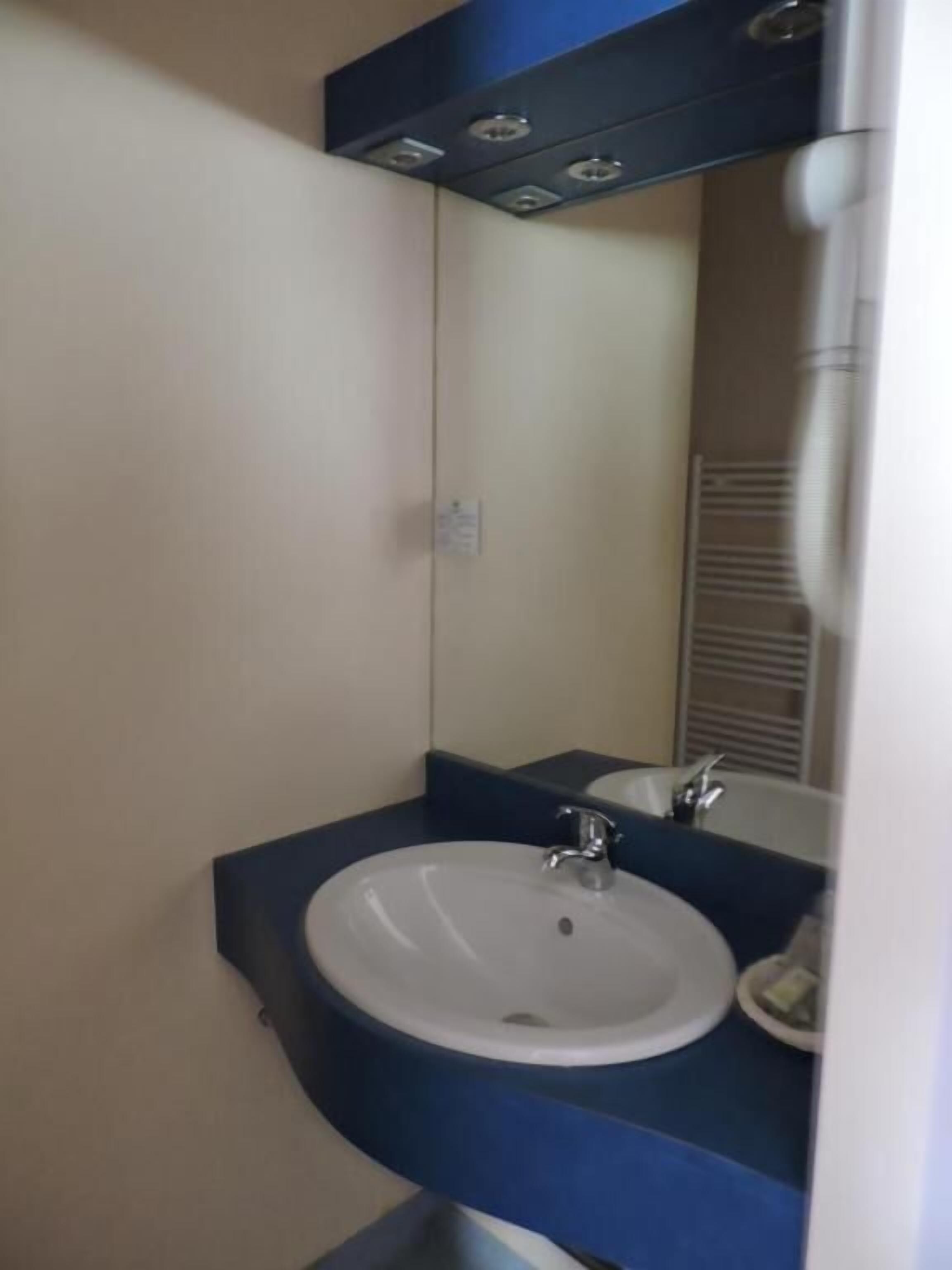 A bathroom with a white sink, a mirror, and a blue countertop.