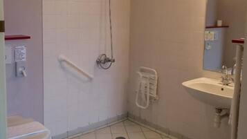 A small, tiled bathroom with a toilet, a shower, and a sink.