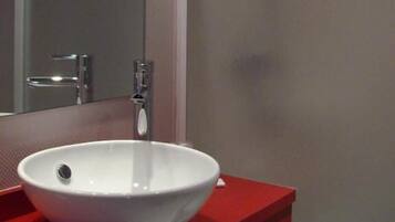 Un baño con un lavamanos blanco, encimera roja y un espejo.