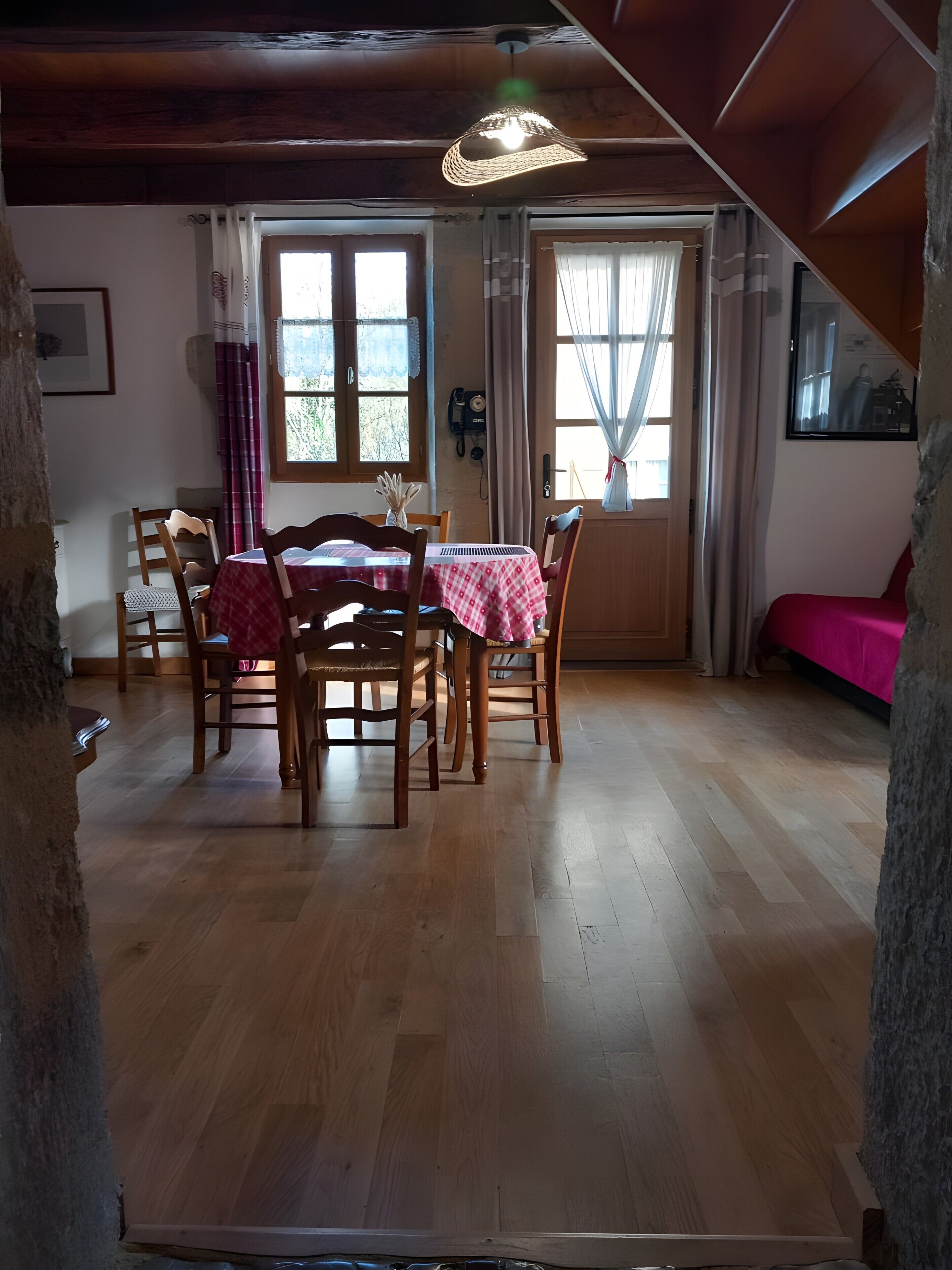 Ein Essbereich mit Holzsesseln und einem Tisch, einem Deckenventilator und einem Fenster mit Vorhängen.