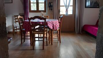 Ein Essbereich mit Holzsesseln und einem Tisch, einem Deckenventilator und einem Fenster mit Vorhängen.
