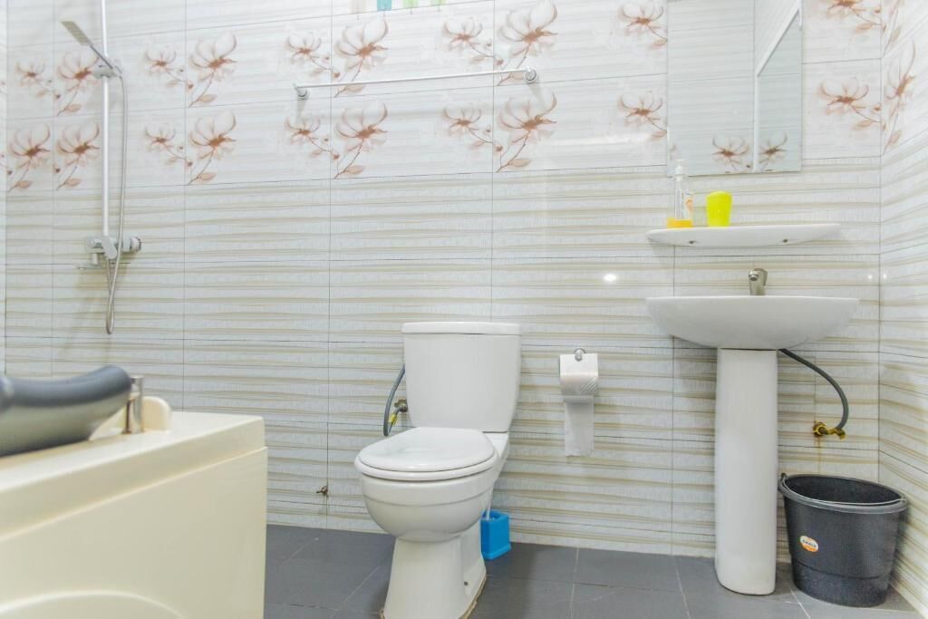 Une salle de bain équipée de toilettes, d’un lavabo, d’une douche et d’une poubelle.