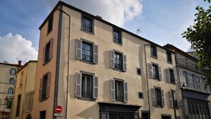 A multi-story building with a beige facade, multiple windows with shutters, and a no entry sign. - 5 chambres en ville (Clermont-Ferrand)