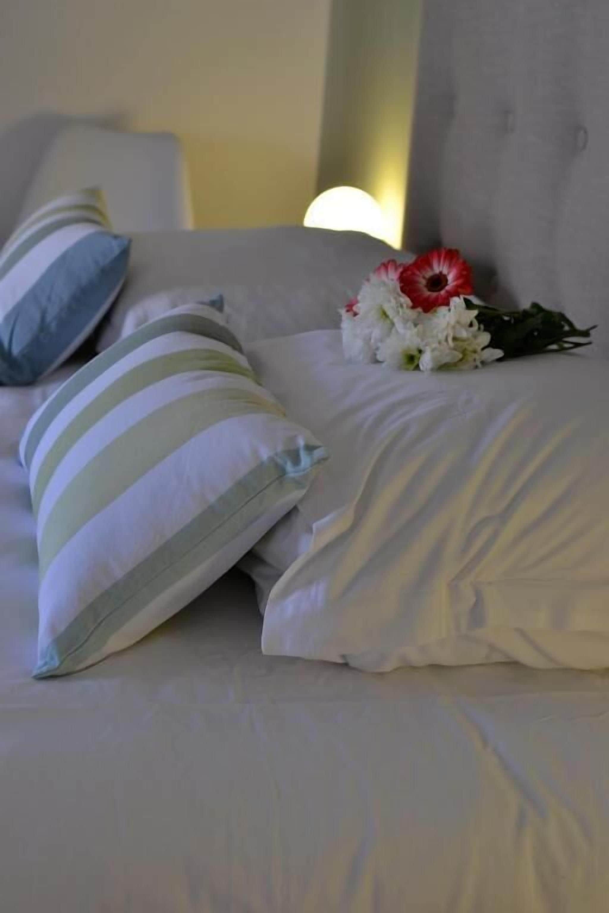 Un lit avec des coussins à rayures et un bouquet de fleurs.