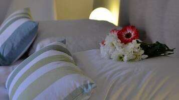 Un lit avec des coussins à rayures et un bouquet de fleurs.
