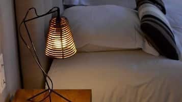 Ett sovrum med en säng, ett sängbord med en lampa och en vägglampa.