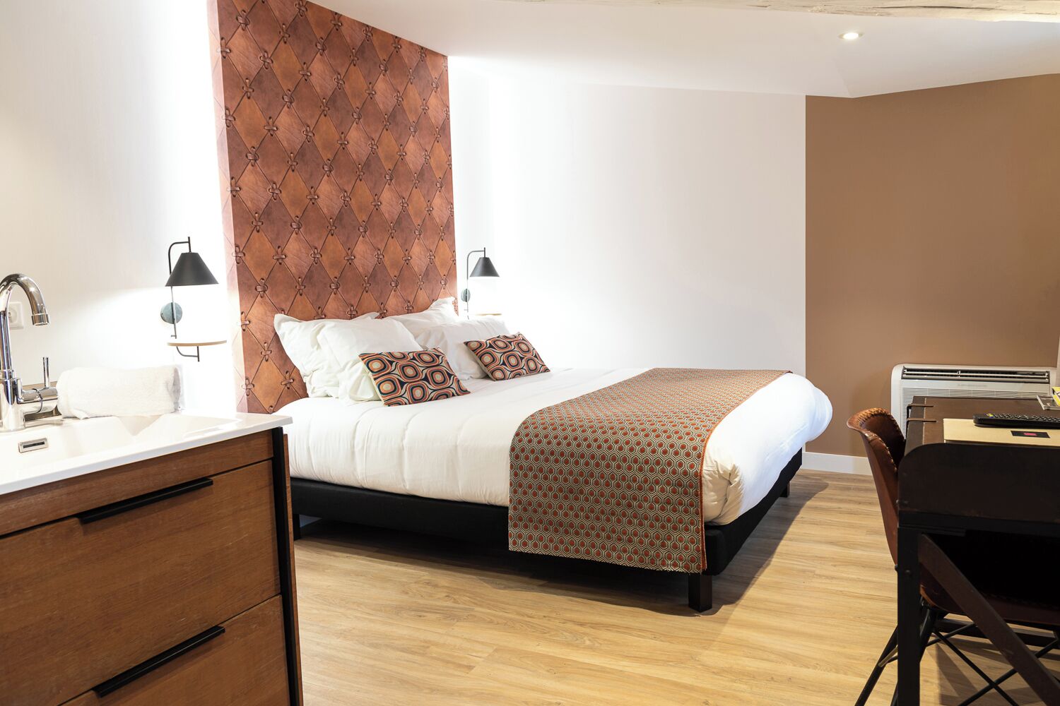 Una habitación de hotel moderna con una cama, mesitas de noche, un escritorio y una silla.