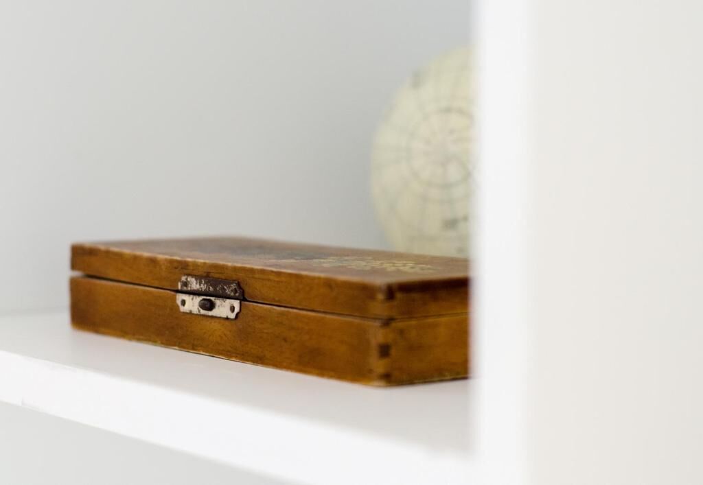 A wooden box with a metal latch on a white shelf.