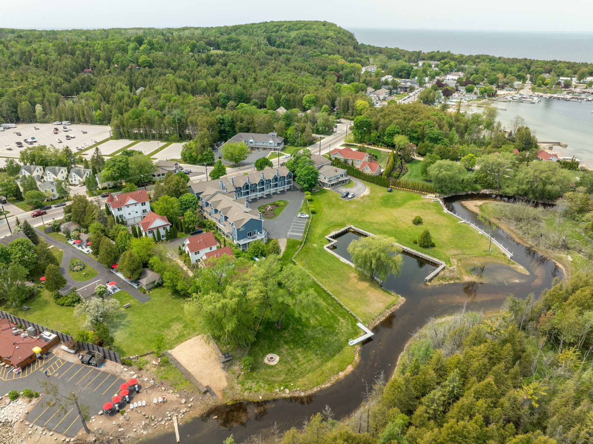 An aerial view of a residential area with houses, a small dock, and a body of water.
