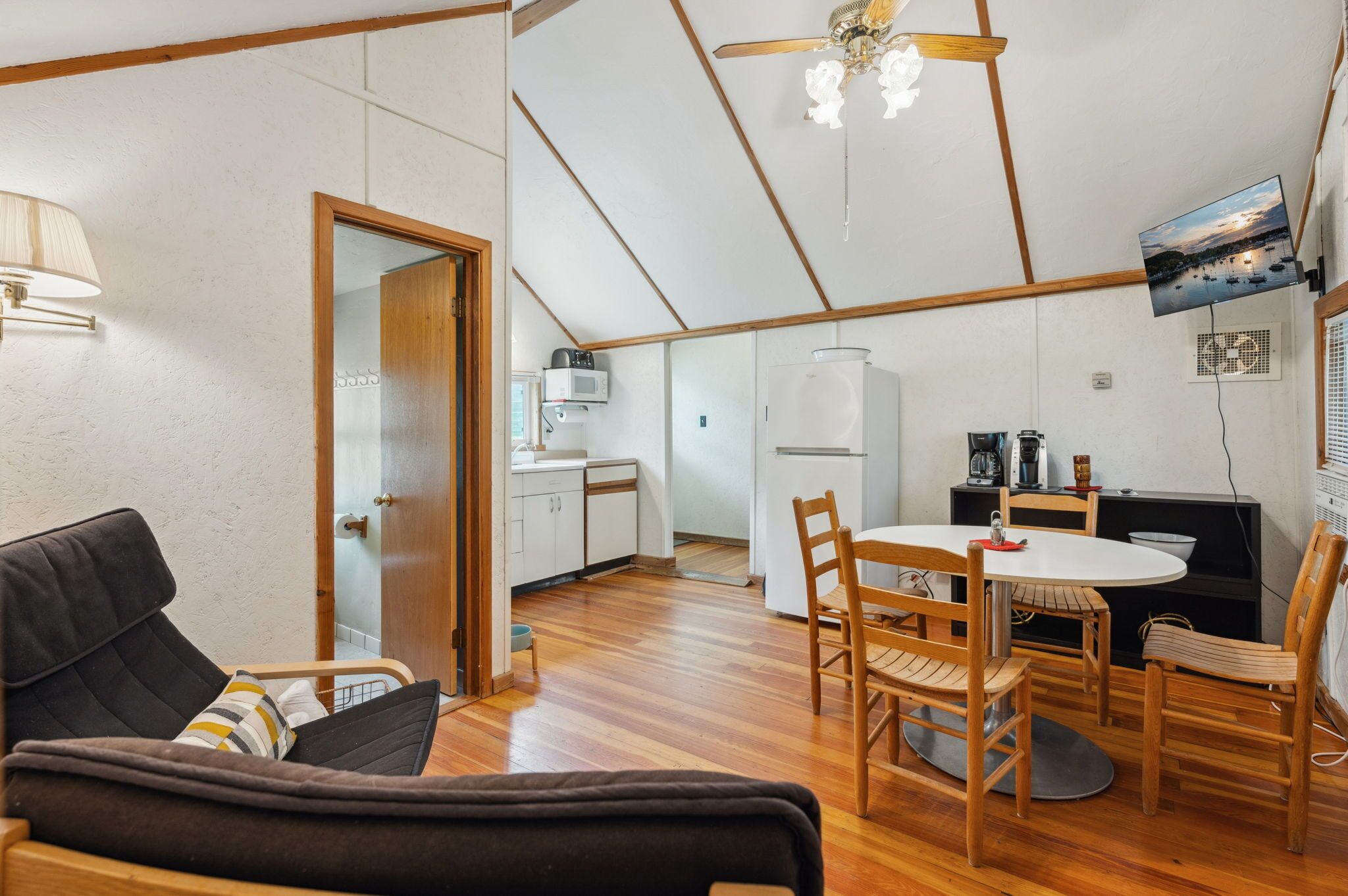 A compact living space with a kitchenette, a dining area, and a seating area with a sofa and chairs.