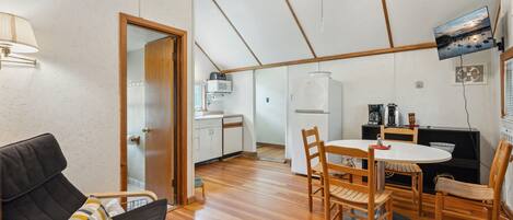 A compact living space with a kitchenette, a dining area, and a seating area with a sofa and chairs.