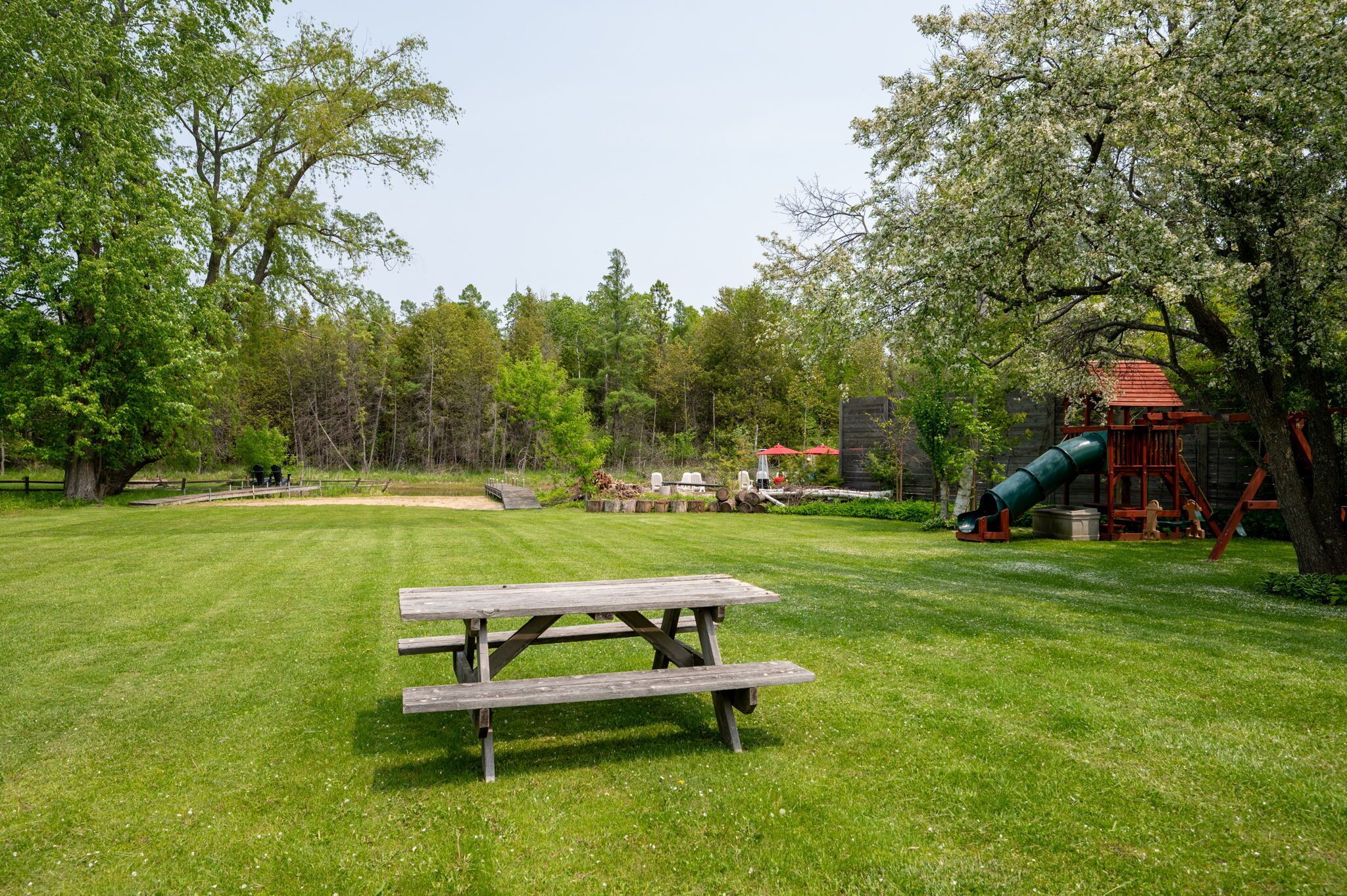 A picnic table in a grassy park area with playground equipment in the background.