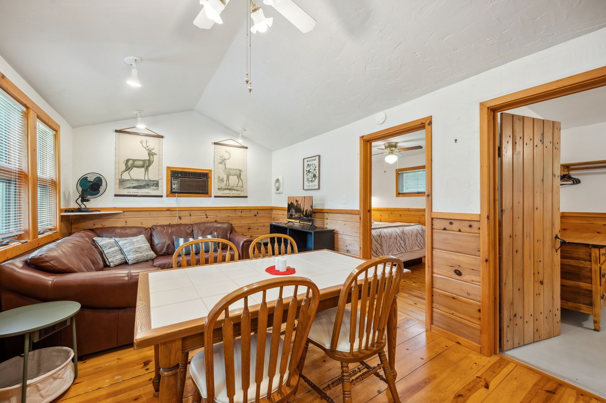A cozy room with a wooden dining table, leather sofa, and a wooden cabinet.
