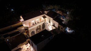 Vista aérea de un edificio de varios pisos con un patio, que incluye un arco de piedra, una escalera y zonas de estar al aire libre.