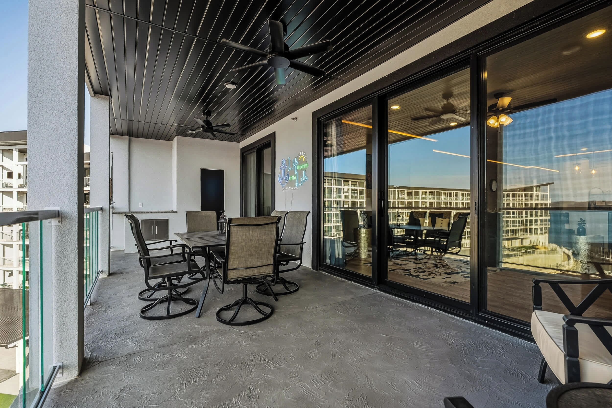 A balcony with a dining table and chairs, a ceiling fan, and a view of a building across the street.