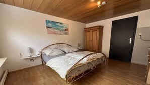 Una camera da letto con un letto, pavimento in legno, un quadro appeso e un armadio.