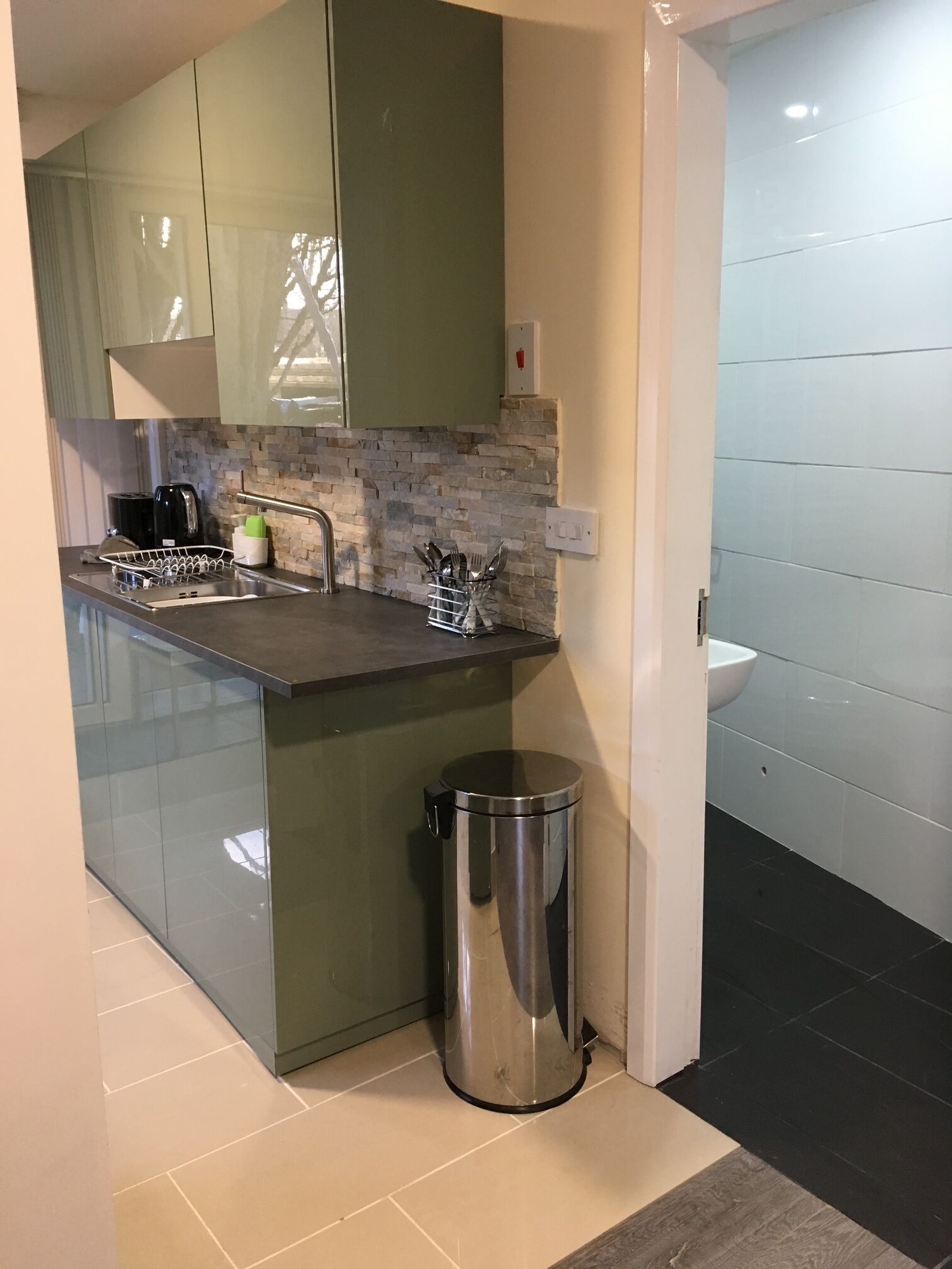A modern kitchen with a sink, a trash bin, and a countertop.