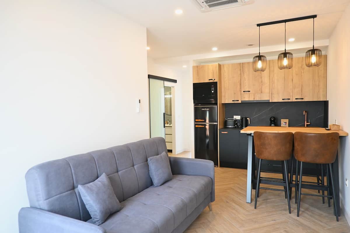 Una cocina moderna con armarios de madera, un refrigerador negro y una cafetera.