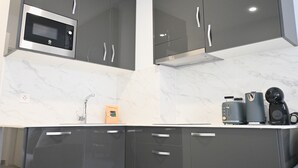 Een moderne keuken met donkere kastjes, een ingebouwde magnetron, een spoelbak en een koffiezetapparaat.