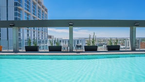 A rooftop pool with a clear view of the cityscape, surrounded by potted plants and seating areas. - Kenect 1816 (Phoenix)