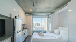 A modern hotel room with a kitchenette, a bed, and a view of the city. - Kenect 1816 (Phoenix)