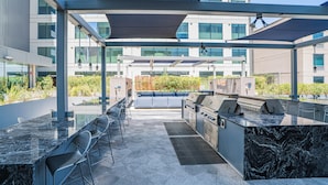 An outdoor patio with a grill, seating area, and a view of the building in the background. - Kenect 1816 (Phoenix)