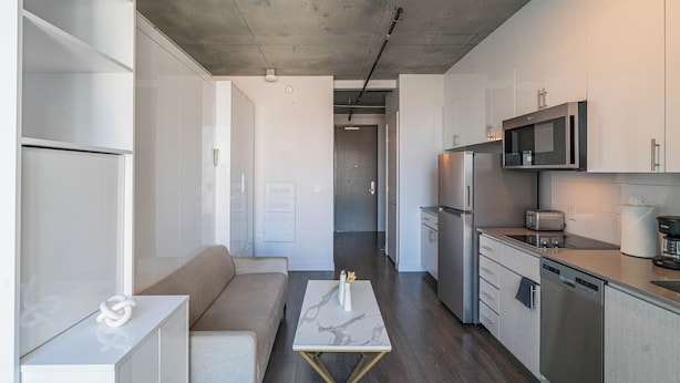 A modern kitchen with white cabinetry, a marble-top table, and a built-in microwave. - Kenect 1816 (Phoenix)