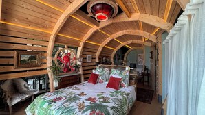 Une chambre à coucher chaleureuse, décorée dans un style rustique avec du bois, comprenant un lit, une décoration représentant un poulpe rouge et un luminaire au plafond.