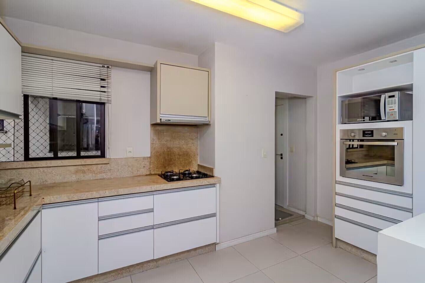 A modern kitchen with white cabinets, a gas stove, and built-in appliances including a microwave and oven.