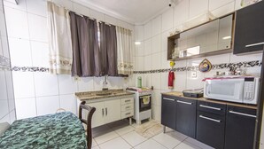Une cuisine compacte avec des carreaux blancs, un four à micro-ondes, un évier et un petit plan de travail.