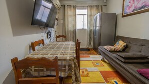 Un espace de vie compact comprenant une table à manger, des chaises, un canapé, un téléviseur et un réfrigérateur.