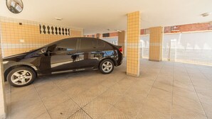 Une voiture noire est garée dans un parking couvert dont les murs et les piliers sont recouverts de carreaux.