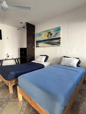Een kamer met twee bedden, een bureau en een schilderij van een strand.