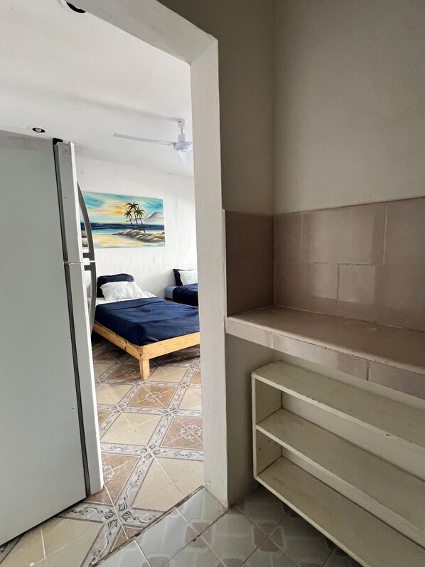 Een slaapkamer met een bed, een schilderij, een witte kledingkast en een betegelde vloer.