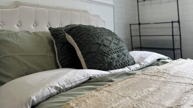 A neatly made bed with a tufted headboard, a bedside shelf, and a wall-mounted rack. - Comfortable Stay with Free Parking (Moor Row)