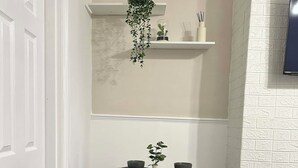 A dining area with a table set for four, a hanging plant, and a shelf with decorative items. - Comfortable Stay with Free Parking (Moor Row)