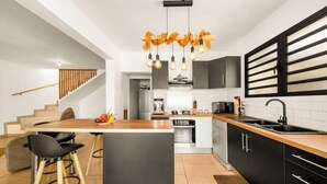 A modern kitchen with a central island, black cabinets, and a wooden countertop. - Villa Rêve Austral (Saint-Pierre)