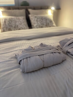 A neatly made bed with a white comforter and two rolled towels. - Top Apartament in Warsaw Center (Warszawa)