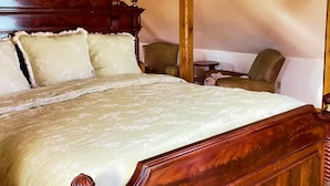Un grand lit avec une tête de lit en bois, une table de chevet en bois et deux chaises.