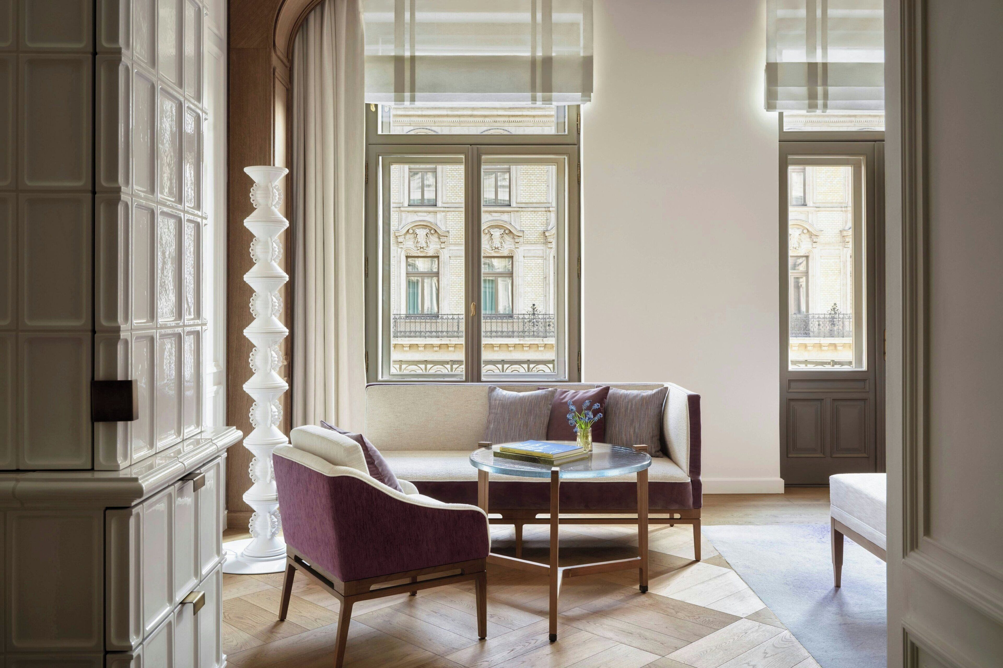A room with a sofa, a chair, a small table, and a decorative pillar.