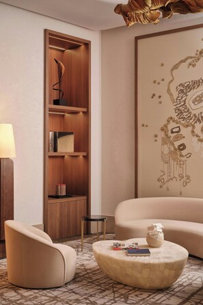 A modern living room with a wooden shelving unit, a round coffee table, a beige sofa, and a decorative wall piece. - The St. Regis Budapest (Budapest)