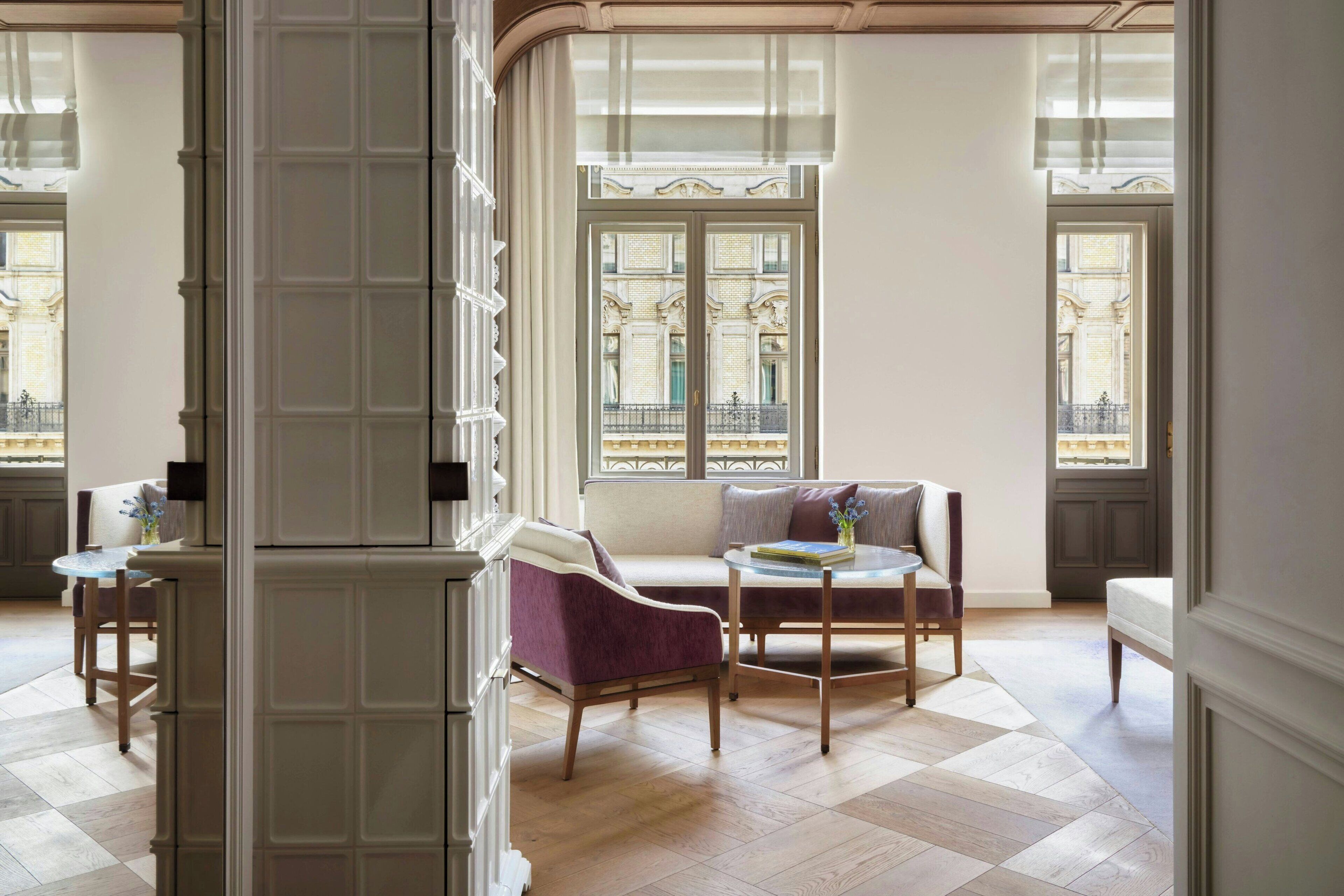 A spacious room with a large window, a sofa, a chair, and a small table.