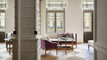 A spacious room with a large window, a sofa, a chair, and a small table.