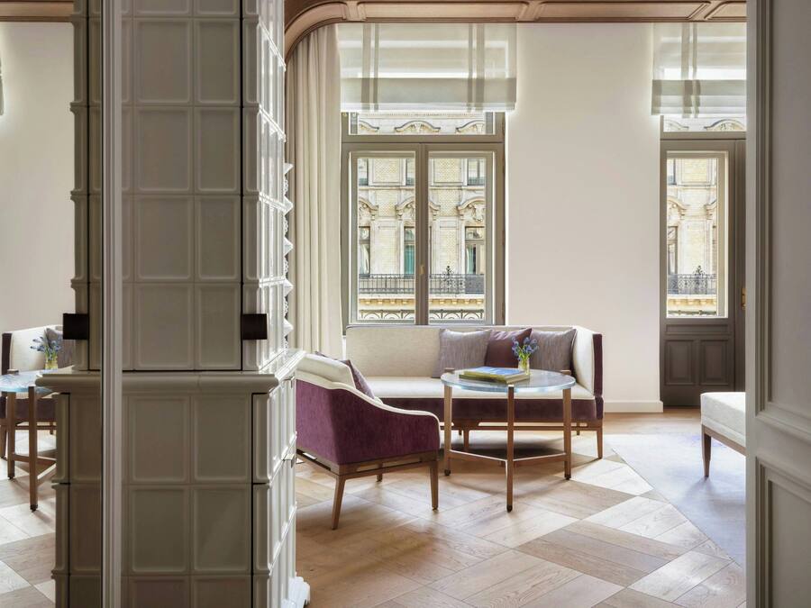 A spacious room with a large window, a sofa, a chair, and a small table.