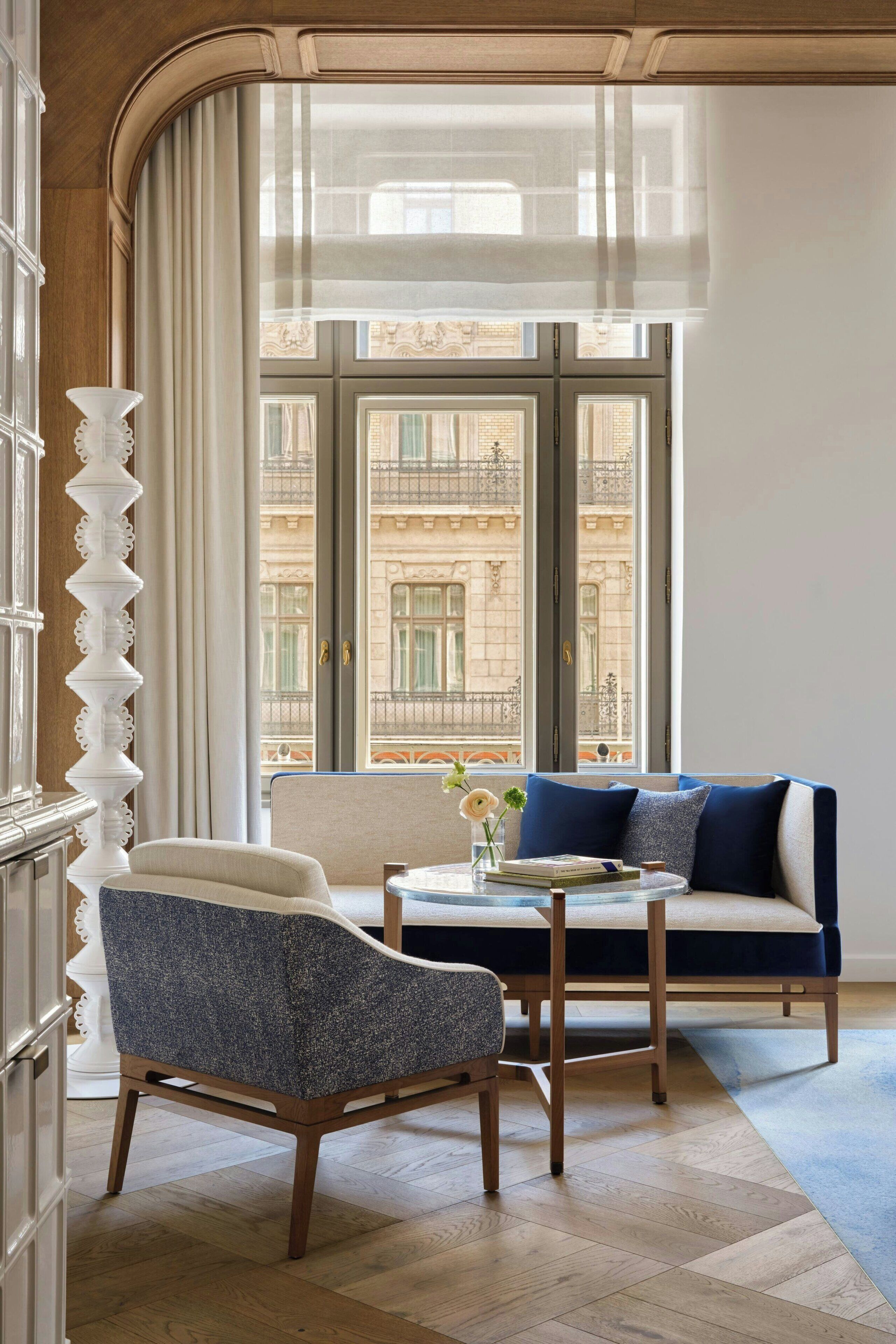 Une pièce comprenant un canapé, un fauteuil et une petite table sur laquelle se trouvent des livres et un vase.
